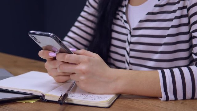 b-roll young woman chatting use smartphone sitting at the desk in modern office. businesswoman wearing casual shirt texting email employee in startup company use cell phone