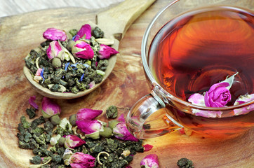 a cup of tea. green tea with flowers in a wooden spoon on a wooden table. green tea with flowers and dry fruit pieces. blend tea. close up