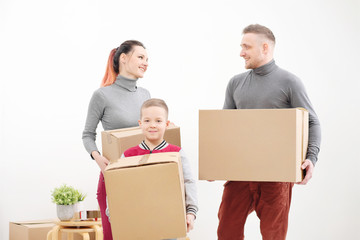 Young family, man woman and child son in new apartments. Carried in the hands of cardboard boxes. Boxes with cargo on a white background.