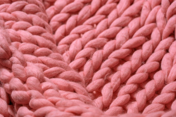 Merino wool handmade knitted large blanket, super chunky yarn, trendy concept. Close-up of knitted blanket, merino wool background. designer blanket made of from pink coral smoky wool