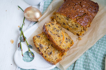 Carrot loaf cake with shiny glaze and nuts on white wooden background close up selective focus