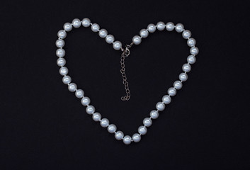 Obraz premium heart shaped pearl necklace on black background