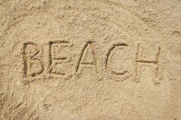 Beach word written on the sand at the beach, natural background