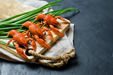 Cooked crayfish on a wooden chopping Board. Black background, top view, space for text.