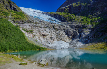 Fototapeta na wymiar Norwegian landscape with milky blue glacier lake, glacier and green mountains. Norway