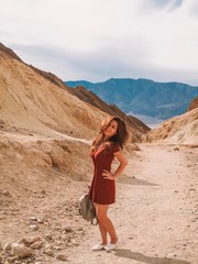 Girl with long hair in a red dress walking on a sandy canyon in the Valley of Death