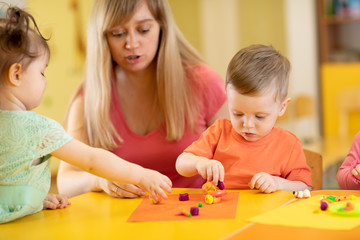 Obraz na płótnie Canvas Little kids molded from clay toys. Teacher or mom play with children.