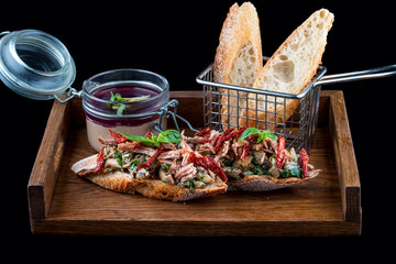 Rabbit pate with bruschetta on a wooden board. On dark background