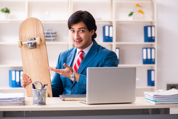 Young handsome businessman with longboard in the office 