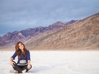 Naklejka na ściany i meble Brunette girl in a plaid shirt with long hair holding a hat on saline soil Badwater in Death Valley