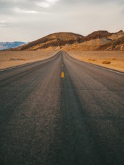 Fototapeta na wymiar Long straight tarmac road heading into the desert of Death Valley 