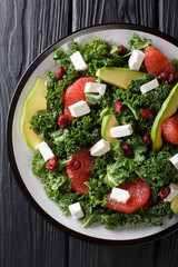 Balanced salad of leaf cabbage, avocado, grapefruit, cheese and dried cranberries close-up on a plate. Vertical top view