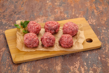 Raw meatball over wooden background