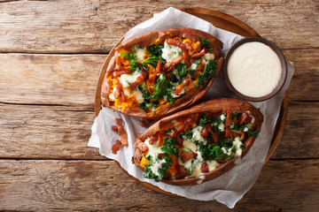 Baked sweet potatoes stuffed with cabbage kale, bacon and cheese sauce close-up. Horizontal top view