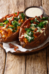 Baked sweet potatoes with kale, bacon and cheese sauce close-up on a plate. vertical