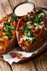 Baked sweet potatoes stuffed with cabbage kale, bacon and cheese sauce close-up. vertical
