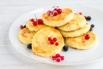 Cottage cheese pancakes with berries on white rustic background