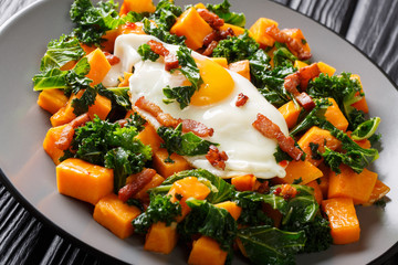 Healthy food sweet potato with kale, bacon and fried egg close-up on a plate. horizontal