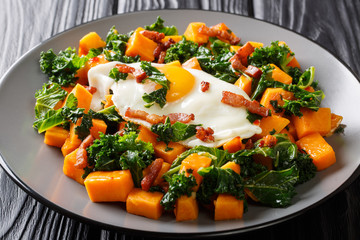 yam with kale, bacon and fried egg close-up on a plate. horizontal