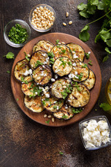Fried eggplant with feta, pine nuts, fresh herbs (cilantro, parsley) and olive oil. Tasty vegetable snack, summer, spring food, picnic