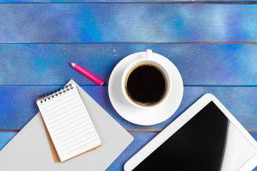 Workplace with blank digital tablet, paper on blue wooden work table. Above view shot