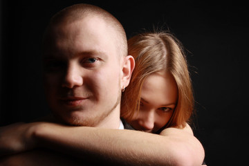 Fototapeta premium Young woman hugs her beloved man from behind