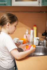Obraz na płótnie Canvas Cute schoolgirl washing plate