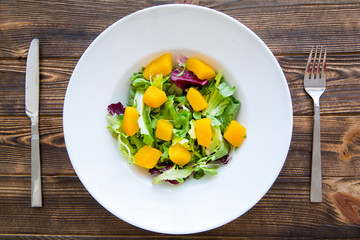 Vegetarian salad on brown wooden table background.