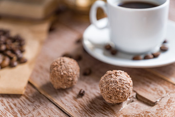 Coffee time break. Cup of freshly breved turk coffee, chocolate balls and book on wooden table
