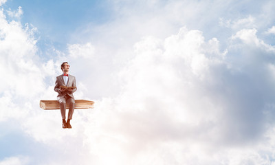 Young businessman or student floating in blue sky and studying the science