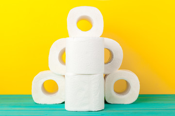 Toilet paper rolls stacked against yellow paper background