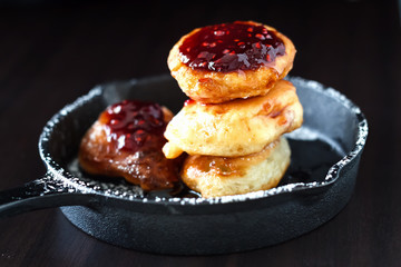 Stack Russian homemade yeast pancakes with Raspberry jam in cast iron skillet. Breakfast concept.