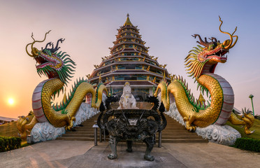 The dragons statue is between the pagoda at sunset