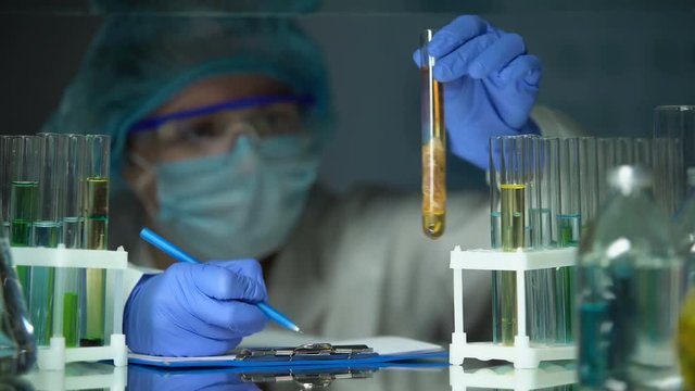 Lab assistant analyzing meat sample in preservative agent and writing results