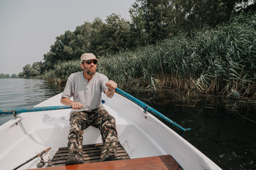 man with beard rowing on rowing boat