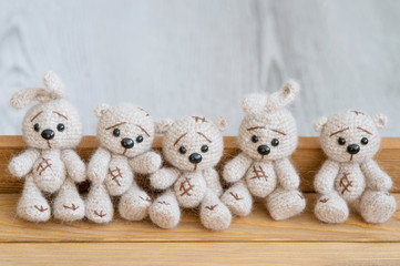 A knitted beige bunnies and bears are sitting on the wooden floor