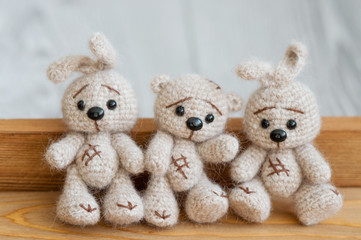 A knitted beige bunnies and bears are sitting on the wooden floor