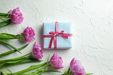 Gift box with beautiful tulips on white textured background