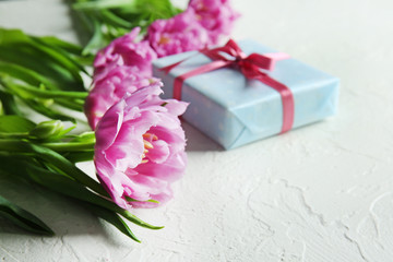 Gift box with beautiful tulips on white textured background