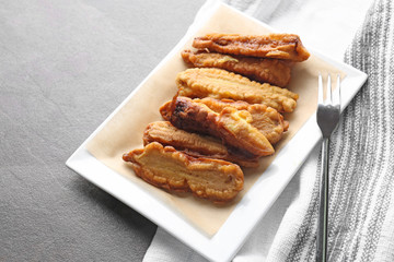 Plate with deep fried baby corn cobs on grey table