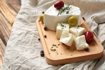 Board with tasty feta cheese and olives on table