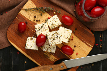 Tasty feta cheese with olives and herbs on wooden board