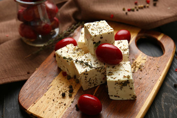 Tasty feta cheese with olives and herbs on wooden board