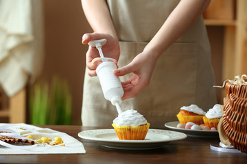 Obraz na płótnie Canvas Woman preparing tasty Easter cupcake in kitchen
