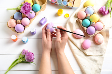 Woman painting Easter eggs at table