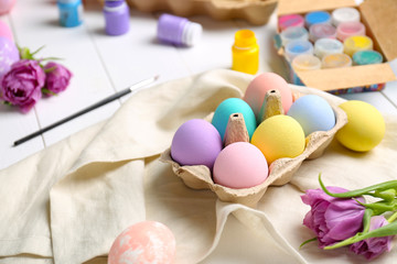 Colorful Easter eggs and paints on table