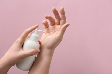 Female hands with bottle of natural cream on color background