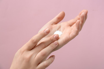 Female hands with natural cream on color background