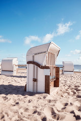 Fototapeta na wymiar Wicker beach chairs on empty sandy beach, color toning applied.
