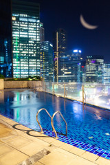 Travel destinations and hotels offering urban retreats and beautiful swimming pools at night in central city location.